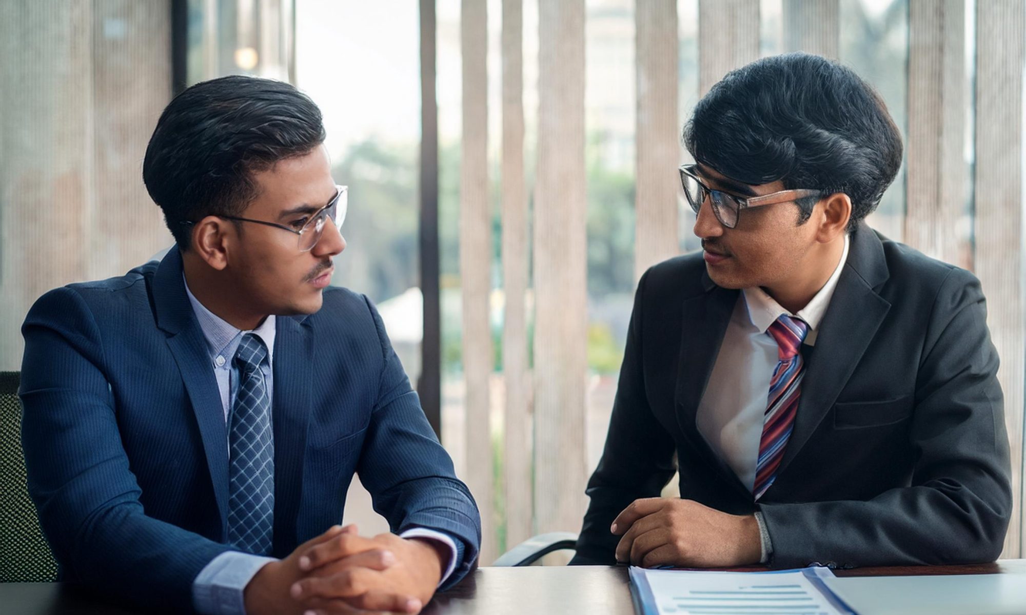 A student and counselor advicing over table, counselor wearing a suit and tie, both can be s